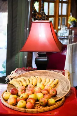 a table with a basket of apples and bananas and a lamp at La Frans Guesthouse in Pretoria