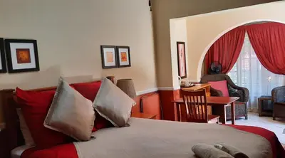 a bedroom with a bed with red pillows at La Frans Guesthouse in Pretoria