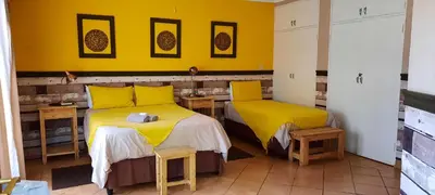 two beds in a room with yellow walls at La Frans Guesthouse in Pretoria