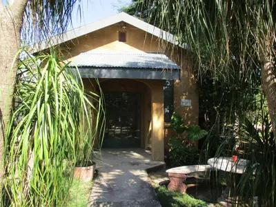 a building with a door and a bench in a garden at Leopard Tree Retreat in Nelspruit