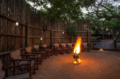 a room with chairs and a fire in front of a fence at Camp Bethel in Hoedspruit