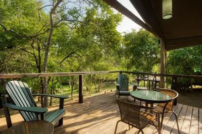 a deck with three chairs and a table on it at Camp Bethel in Hoedspruit