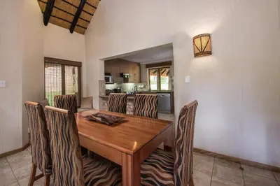 a dining room with a wooden table and chairs at Kruger Park Lodge Unit No. 277 in Hazyview