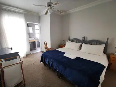 a bedroom with a large bed with a blue blanket at Meintjieskop Self-Catering Accommodation in Pretoria
