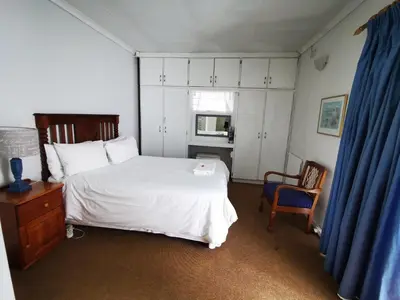 a bedroom with a white bed and a blue curtain at Meintjieskop Self-Catering Accommodation in Pretoria
