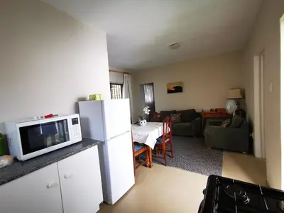 a kitchen with a white refrigerator and a living room at Meintjieskop Self-Catering Accommodation in Pretoria