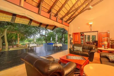 a living room with leather furniture and a large window at Mvuradona Safari Lodge in Marloth Park