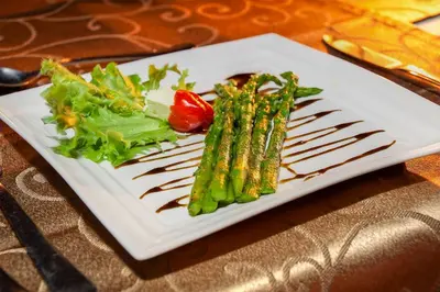 a plate with asparagus and vegetables on a table at Mvuradona Safari Lodge in Marloth Park