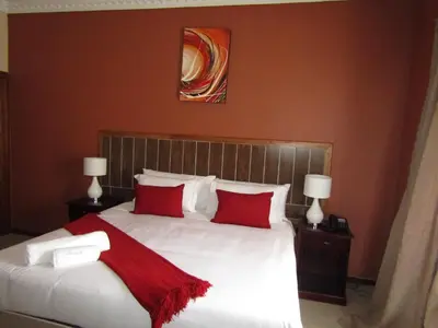 a bedroom with a large white bed with red pillows at Vido Lodge and Conference Centre in Polokwane