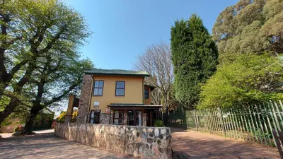 a yellow house with a fence in front of it at Catmandu in Dullstroom
