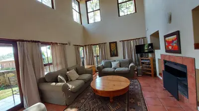 a living room with couches and a table and a tv at Catmandu in Dullstroom