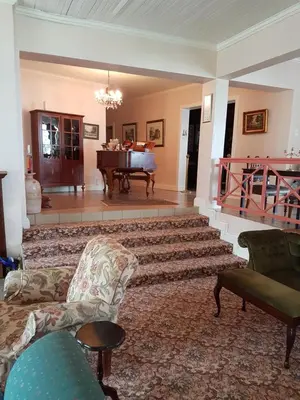 a living room with a couch and a piano at Sherwood's Country House in Tzaneen