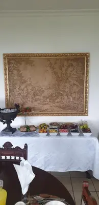 a table with plates of food on it with a painting at Sherwood's Country House in Tzaneen