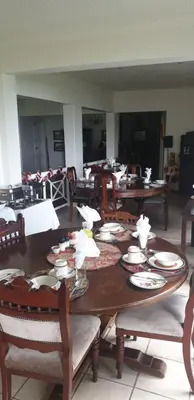 a wooden table with chairs and plates on it at Sherwood's Country House in Tzaneen