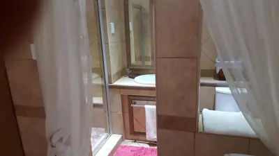 a bathroom with a sink and a toilet and a mirror at Bubez Guesthouse in Barberton