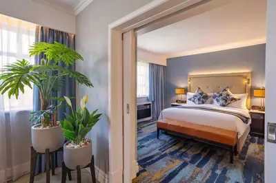 a hotel room with a bed and two plants at Southern Sun Mbombela in Nelspruit