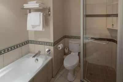 a bathroom with a toilet and a sink and a shower at Southern Sun Mbombela in Nelspruit