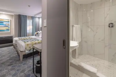 a hotel room with a bathroom with a bed and a shower at StayEasy Mbombela in Nelspruit