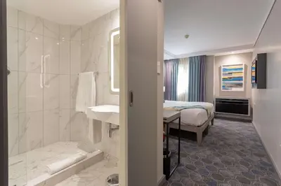 a hotel room with a bathroom with a bed at StayEasy Mbombela in Nelspruit