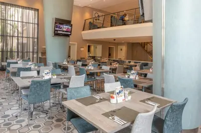 a restaurant with tables and chairs and a balcony at StayEasy Mbombela in Nelspruit