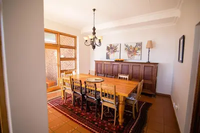 a dining room with a wooden table and chairs at Spitskop Plaashuis in Lydenburg