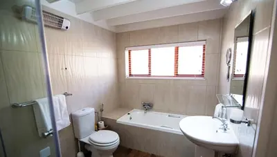 a bathroom with a toilet and a tub and a sink at Galashiels in Dullstroom