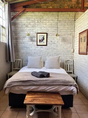 a bedroom with a large bed with a brick wall at Green Thumb Farm Stay in Ermelo