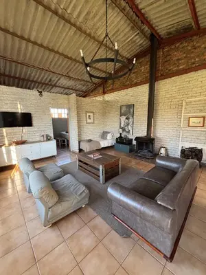 a living room with a leather couch and a fireplace at Green Thumb Farm Stay in Ermelo