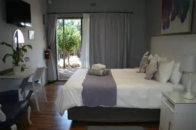 a bedroom with a bed and a desk and a window at Purdy's Place in Louis Trichardt