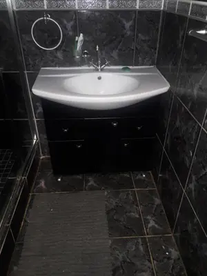 a white sink in a black tiled bathroom at Tehilah in Sabie