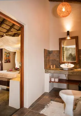 a bathroom with a toilet and a sink and a bed at Lamai Safari Lodge in Balule Game Reserve