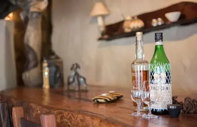 a bottle of wine and two glasses on a wooden table at Lamai Safari Lodge in Balule Game Reserve