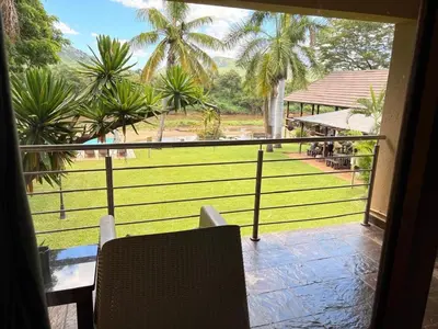 a balcony with a view of a field and palm trees at Rio Vista Lodge in Malelane
