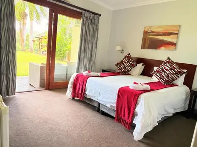 a bedroom with two beds and a sliding glass door at Rio Vista Lodge in Malelane