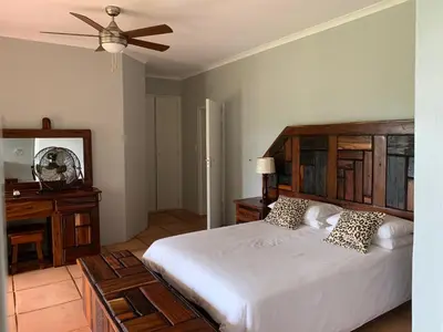 a bedroom with a large white bed and a ceiling fan at Kransberg Country Lodge Guest Farm in Thabazimbi