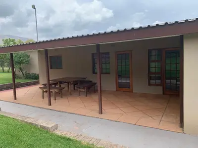 a house with a patio with a table and benches at Kransberg Country Lodge Guest Farm in Thabazimbi