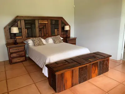 a bedroom with a large bed with a wooden headboard at Kransberg Country Lodge Guest Farm in Thabazimbi