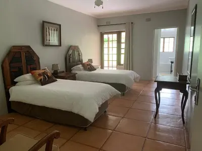 a bedroom with two beds and a table and a desk at Kransberg Country Lodge Guest Farm in Thabazimbi