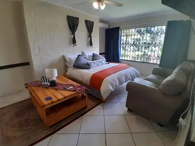 a bedroom with a bed and a couch and a window at Yacht View Lodge in Schoemansville
