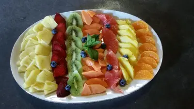 a white plate of fruit on a table at Call of the Wild Lodge in Hoedspruit