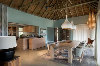 a kitchen and dining room with a wooden table and chairs at MHONDORO SAFARI LODGE & VILLA in Welgevonden Game Reserve