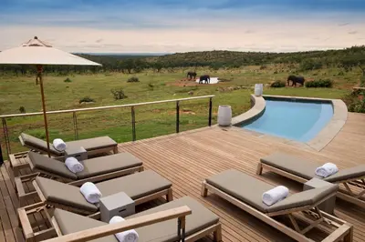 a deck with lounge chairs and a swimming pool at MHONDORO SAFARI LODGE & VILLA in Welgevonden Game Reserve