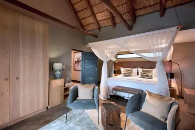 a bedroom with a bed and two chairs at MHONDORO SAFARI LODGE & VILLA in Welgevonden Game Reserve
