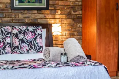 a bedroom with a bed with a brick wall at Berghaan Pretoria in Pretoria