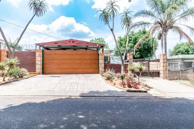 a garage with a wooden garage door and palm trees at Berghaan Pretoria in Pretoria
