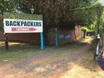 a sign for a back packers entrance next to a building at Sabie Gypsy's Backpackers in Sabie