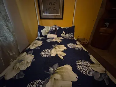 a bed with a blue comforter with flowers on it at Sabie Gypsy's Backpackers in Sabie