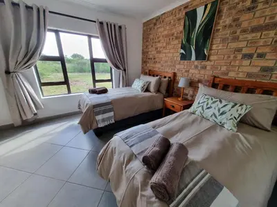 a bedroom with two beds and a brick wall at Sondela Nature Reserve & Spa Chalets in Bela-Bela