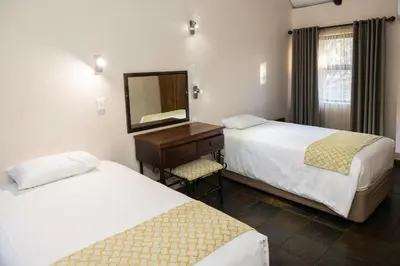a bedroom with two beds and a dresser with a mirror at Phalaborwa Safari Park, A Forever Resort in Phalaborwa