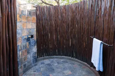 a shower with a wooden fence in a bathroom at Phalaborwa Safari Park, A Forever Resort in Phalaborwa